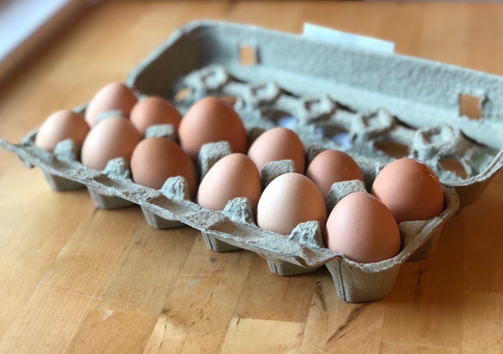 A carton of one dozen fresh Rootbound eggs atop a table.